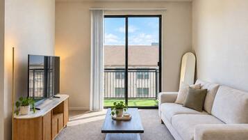 A modern living room with a flat-screen TV, a wooden cabinet, a coffee table, and a sofa.