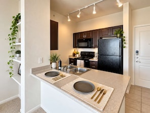 A modern kitchen with a central island, stainless steel appliances, and a white door.