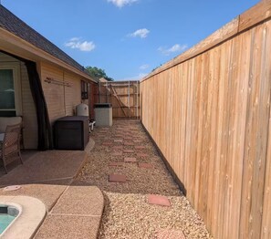 A backyard with a patio area, a pool, and a wooden fence. - A Relaxing Denton Oasis (Denton)