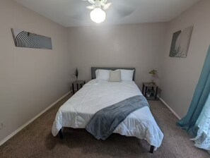 A bedroom with a bed, two bedside tables, a nightstand, a ceiling fan, and a wall-mounted light fixture. - A Relaxing Denton Oasis (Denton)