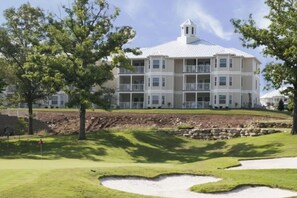 A multi-story building with balconies, surrounded by a well-maintained lawn and a sand bunker. - 2-bedroom hotel in perfect Branson with fitness room and AC / 1364m (Branson)