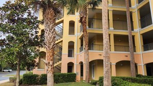 A multi-story building with balconies, surrounded by palm trees and well-maintained landscaping. - Sunshine, Comfort & Magic in Orlando (Orlando)