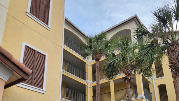 A multi-story building with balconies, palm trees, and a well-maintained hedge. - Sunshine, Comfort & Magic in Orlando (Orlando)