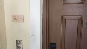 A brown door with a keypad lock, a room number sign, and a button for a handicapped-accessible room. - Sunshine, Comfort & Magic in Orlando (Orlando)