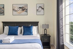 A hotel room with a bed, pillows, a nightstand, a lamp, and artwork on the wall. - A Relaxing Getaway & More! M452 (Orlando)