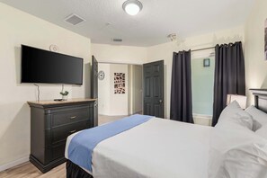 A hotel room with a bed, a dresser, a television, and a door leading to another room. - A Relaxing Getaway & More! M452 (Orlando)