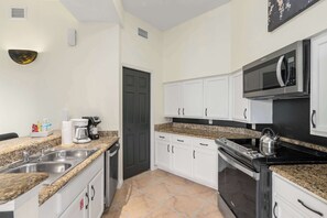 A modern kitchen with granite countertops, white cabinets, a built-in microwave, and a stove. - A Relaxing Getaway & More! M452 (Orlando)