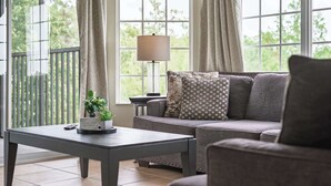 Ein Zimmer mit einem grauen Sofa, einem kleinen Tisch mit einer Pflanze und einer Lampe.