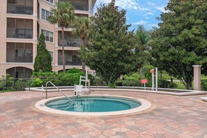 Piscina com área pavimentada ao redor, um banco e um corrimão.