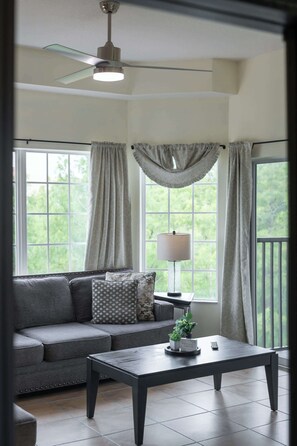 A living room with a sofa, a coffee table, a lamp, and a ceiling fan. - A Relaxing Getaway & More! M452 (Orlando)