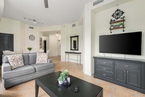 Uma sala de estar com sofá, mesa de centro, televisão e um móvel de TV com gavetas.
