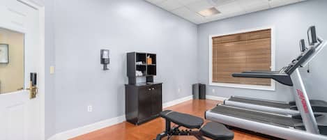 Un gimnasio en casa con cinta de correr, banco y espacio de almacenamiento.