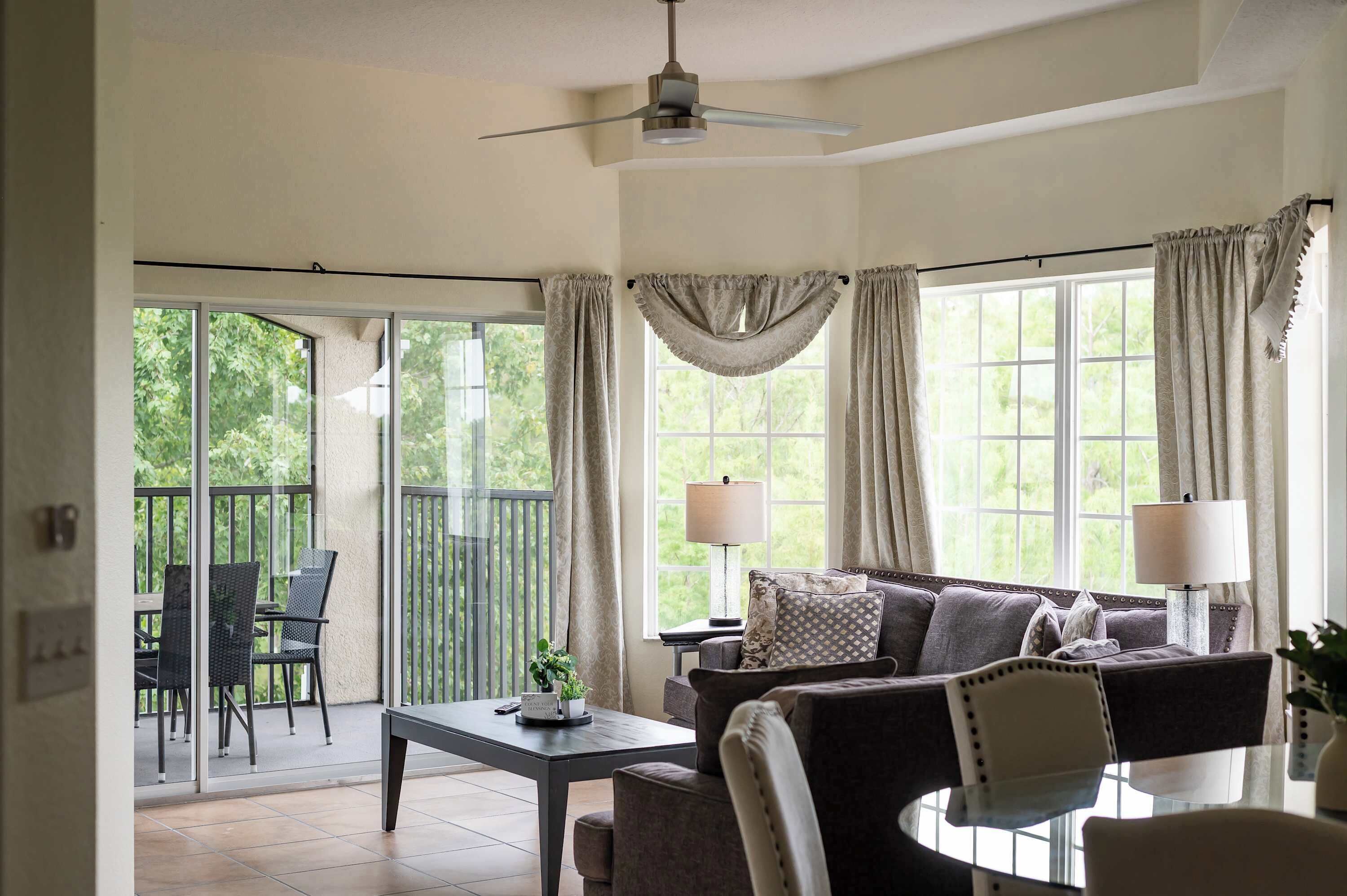A living room with a sofa, two lamps, a table, and a ceiling fan.