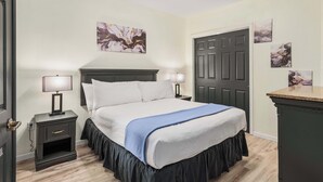 Ein Hotelzimmer mit einem Bett, Nachttischen, einer Kommode und Kunstwerken an den Wänden.
