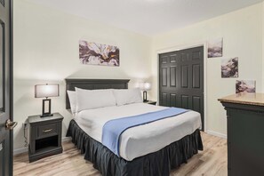 Ein Hotelzimmer mit einem Bett, Nachttischen, einer Kommode und Kunstwerken an den Wänden.