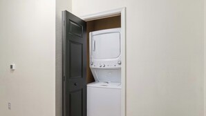 Ein Waschraum mit Waschmaschine und Trockner, einer Tür und einem Lichtschalter an der Wand.