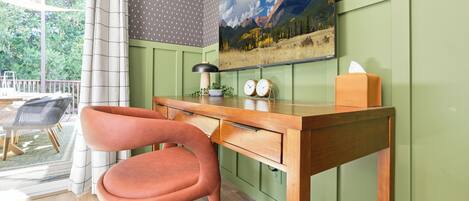 A room with a desk, a chair, a clock, a tissue box, and a painting on the wall.