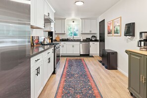 A modern kitchen with white cabinetry, stainless steel appliances, and a patterned rug. - Newly Renovated Home Near Yosemite & Bass Lake - Sauna, Hot Tub, Games (Oakhurst)