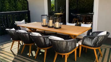 An outdoor patio with a wooden table and chairs, surrounded by a green and beige striped rug.