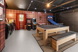 A room with a ping pong table, a dartboard, arcade games, and a blue slide. - Newly Renovated Home Near Yosemite & Bass Lake - Sauna, Hot Tub, Games (Oakhurst)