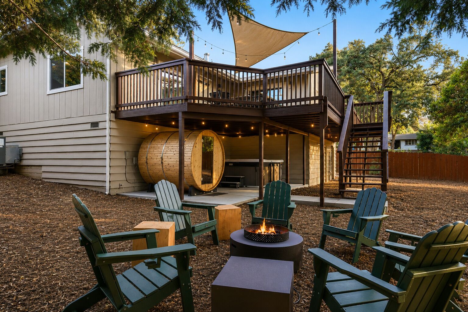 An outdoor deck with Adirondack chairs, a fire pit, and a wooden barrel.