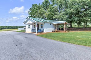 A single-story house with a porch, a small table and chairs, and a covered area with benches. - The Country Store at Clemson (Anderson County)
