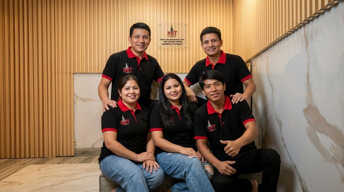 A group of people in black and red shirts seated and standing in a room with wooden paneling and a marble floor.