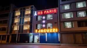 A hotel with a neon sign reading 'HS PARIS' and 'IJACUZZI' indicating a restaurant or bar.