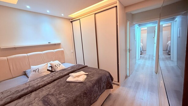 Ein modernes Schlafzimmer mit Bett, Kleiderschrank und Spiegel.