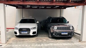 Zwei Autos stehen unter einer überdachten Fläche mit Betonboden.
