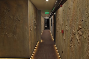 A hallway with textured walls, a patterned carpet, and an exit sign.