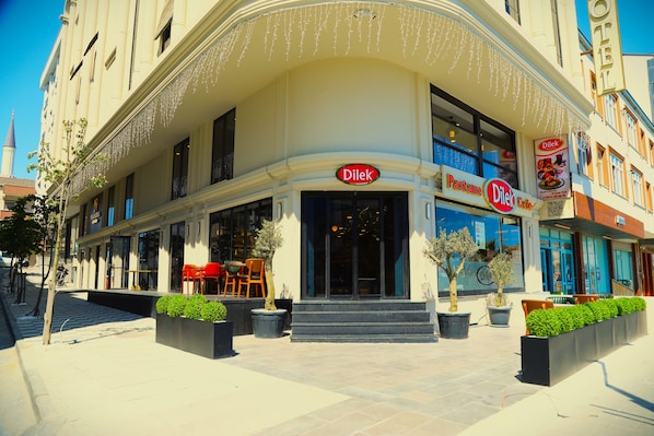 A hotel with a Dilek Cafe sign, outdoor seating, and a staircase leading to the entrance.