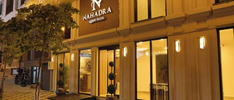 A hotel entrance with a checkered floor, potted plants, and a sign reading 'NAHADRA AIRPORT HOTEL'.