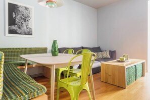 Ein stilvoller Wohnraum mit einem runden Tisch, grünen Stühlen, einer Couch und einem kleinen Holztisch.