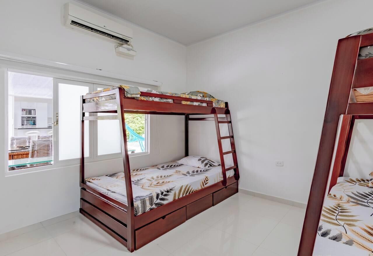 A single-bed room with a wooden bunk bed, a window with a view, and an air conditioning unit.