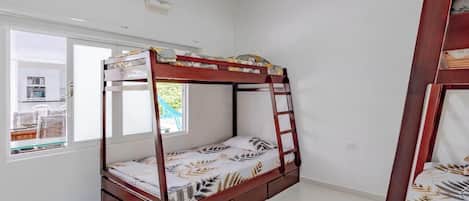A single-bed room with a wooden bunk bed, a window with a view, and an air conditioning unit.