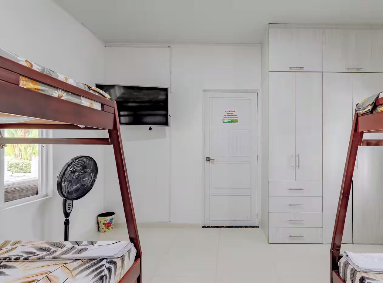 A bedroom with bunk beds, a television, a wardrobe, and a door with a sign.