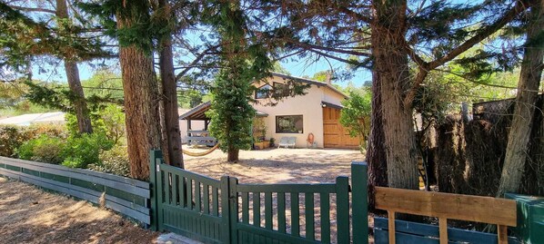 Ein Haus mit eingezäunter Garten, einer Holzterrasse und einem Picknicktisch.