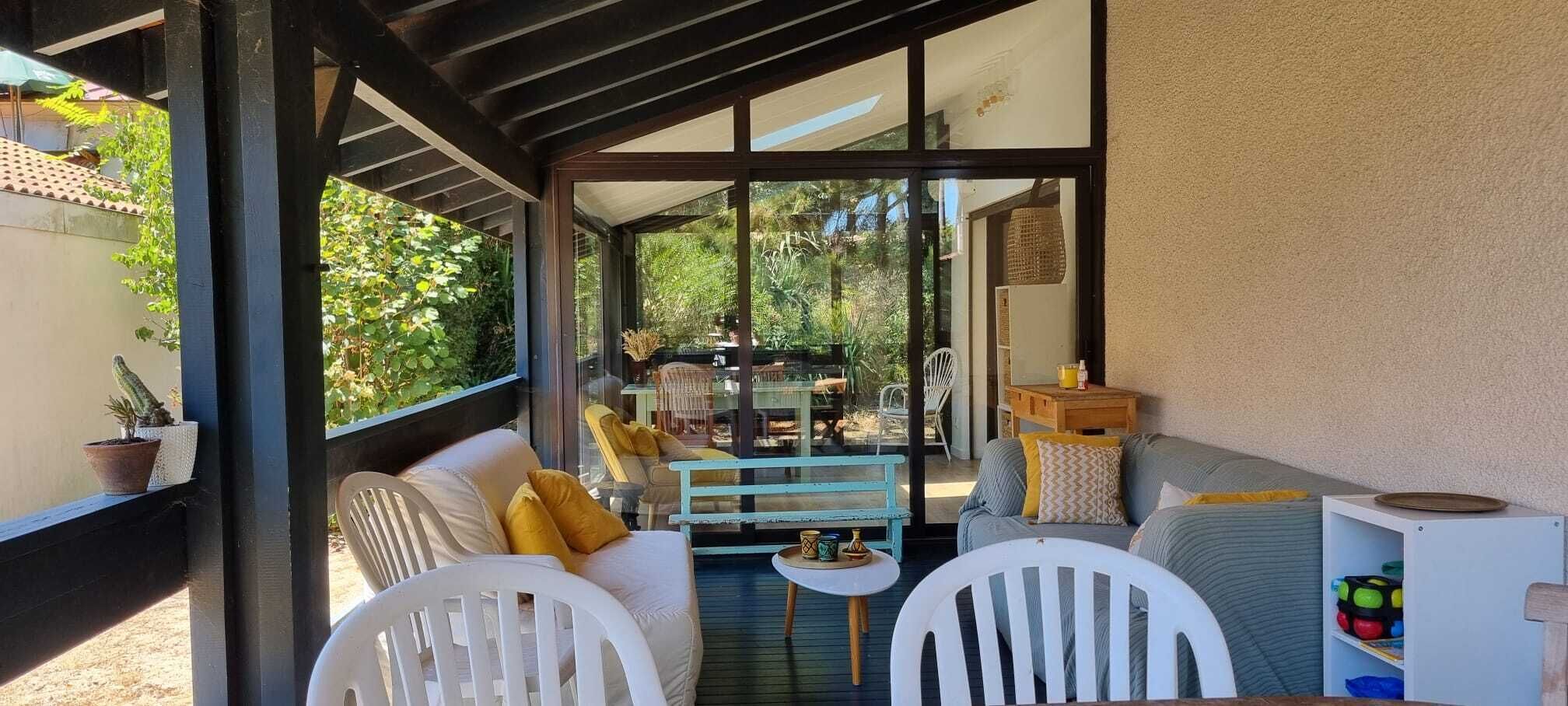 Un espace extérieur aménagé avec des meubles blancs, une petite table et une plante en pot, le tout abrité.