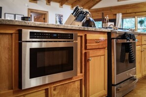 Eine Küche mit Edelstahlgeräten, Holzschränken und einer Arbeitsplatte mit Küchenutensilien.