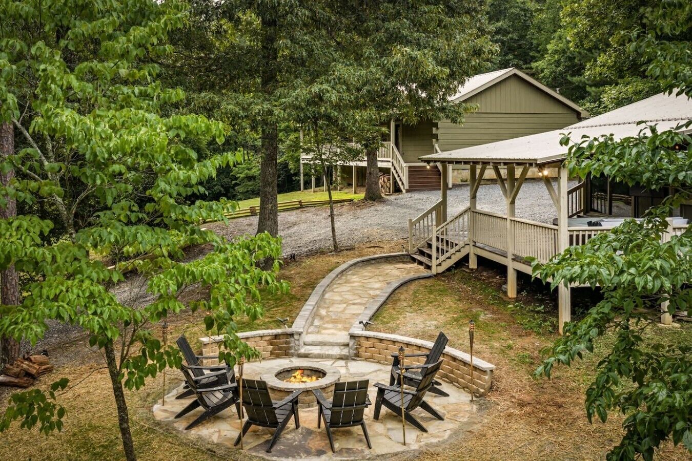 A patio area with a fire pit and seating, surrounded by trees and a wooden deck.