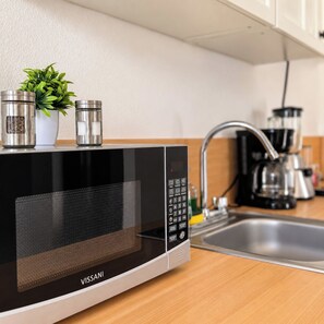 A modern kitchen with a black Vissani microwave, a stainless steel sink, and a coffee maker. - Pichilingue Housing cerca del malecon (La Paz)