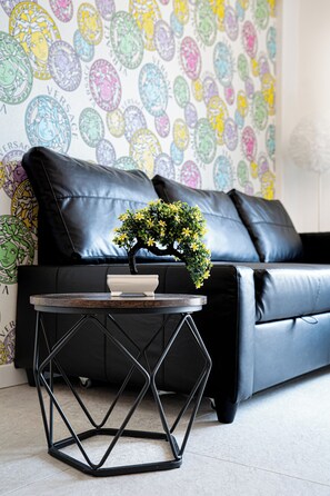 A black leather sofa with a decorative wall in the background. - Florence Dream Homes - Medusa (Firenze Fl)