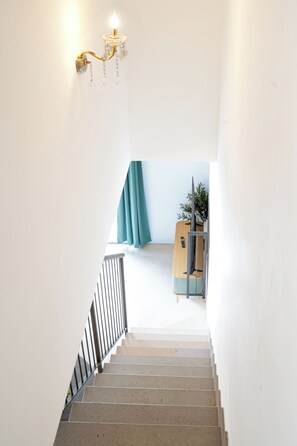 A staircase leading to a room with a bed, a plant, and a desk with a computer. - Florence Dream Homes - Medusa (Firenze Fl)