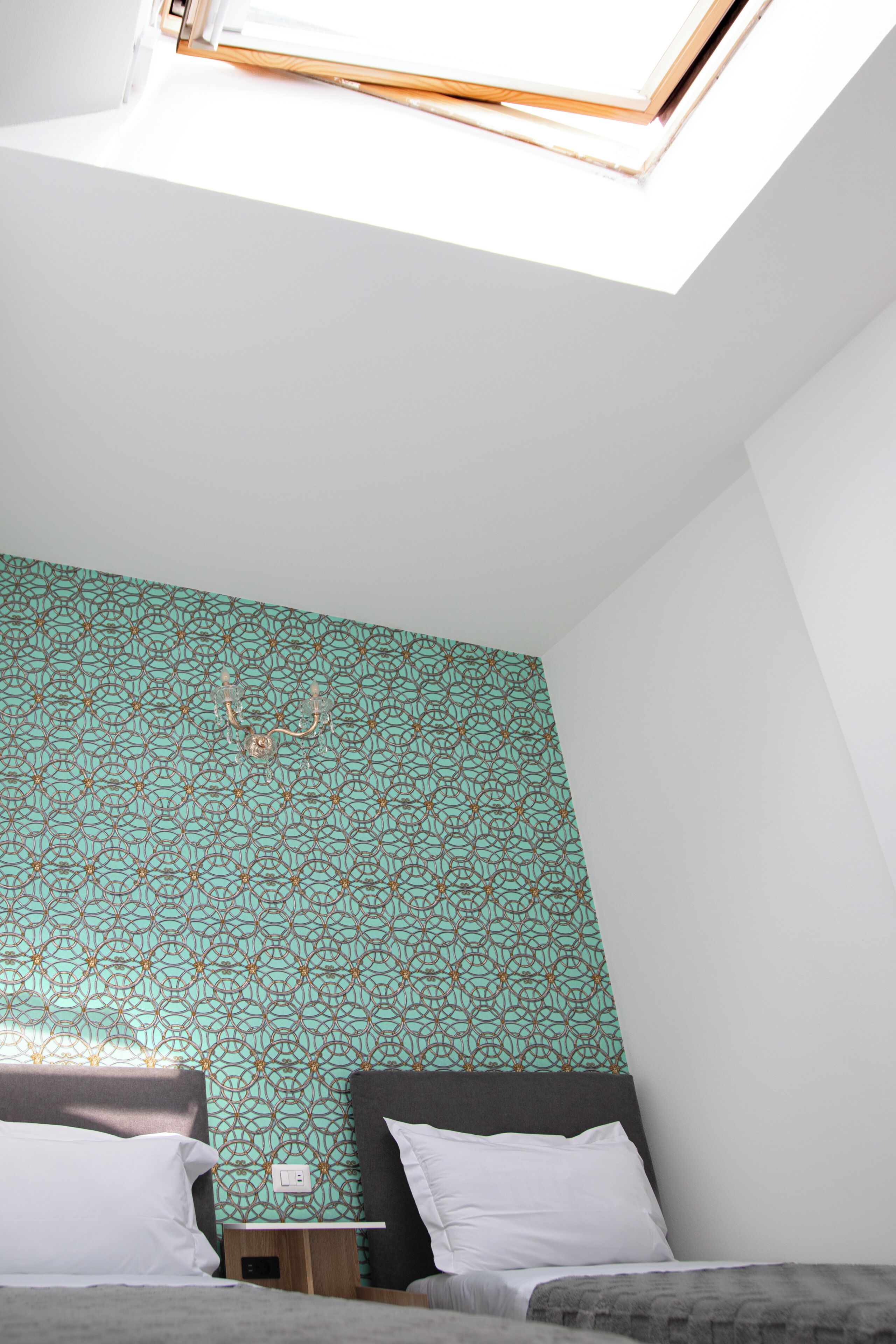 Ein Zimmer mit zwei Betten, einem kleinen Tisch und einem Dachfenster.