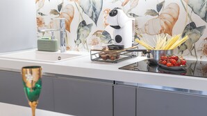 Een keuken met een modern design, voorzien van een spoelbak, waterkoker en een pan op het aanrecht.