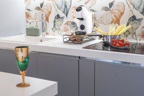 A kitchen with a modern design, featuring a sink, a kettle, and a pot on the countertop. - Florence Dream Homes - Medusa (Firenze Fl)