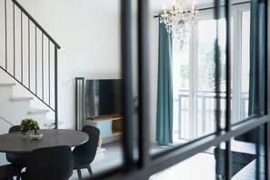 Ein modernes Wohnzimmer mit Treppe, Essbereich und großem, mit Vorhängen versehenen Fenster.