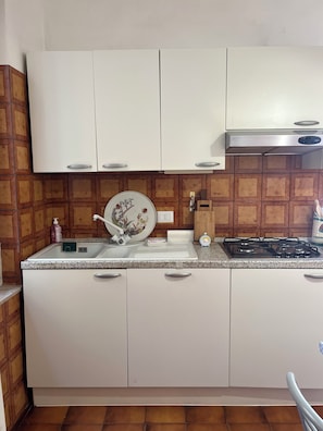 Una cucina con mobili bianchi, un piano di lavoro in granito, un fornello e un lavandino.