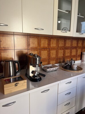 Una cucina con una macchina del caffè, un bollitore e un vassoio con barattoli.